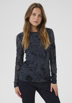 Long-sleeve navy top featuring floral embroidery, sheer sleeves, and a textured body with a round neckline and fitted design.