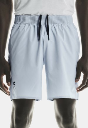 Ljusblå sportshorts med resårmidja, svarta snoddar och en liten logotyp på vänster ben. Slät textur, knä-lång passform.