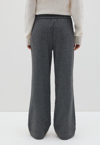 Pantaloni larghi grigi con un tessuto testurizzato, caratterizzati da una vita piatta e un design pulito. Sottiglie variazioni di tonalità arricchiscono l'interesse visivo.