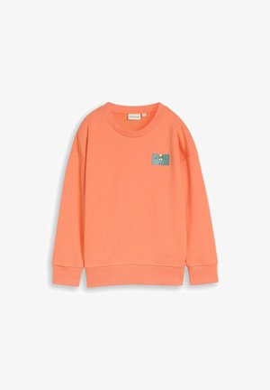 Sweat-shirt corail orange à col rond, manches longues, avec un petit patch rectangulaire représentant un chien dessin animé sur la poitrine gauche.