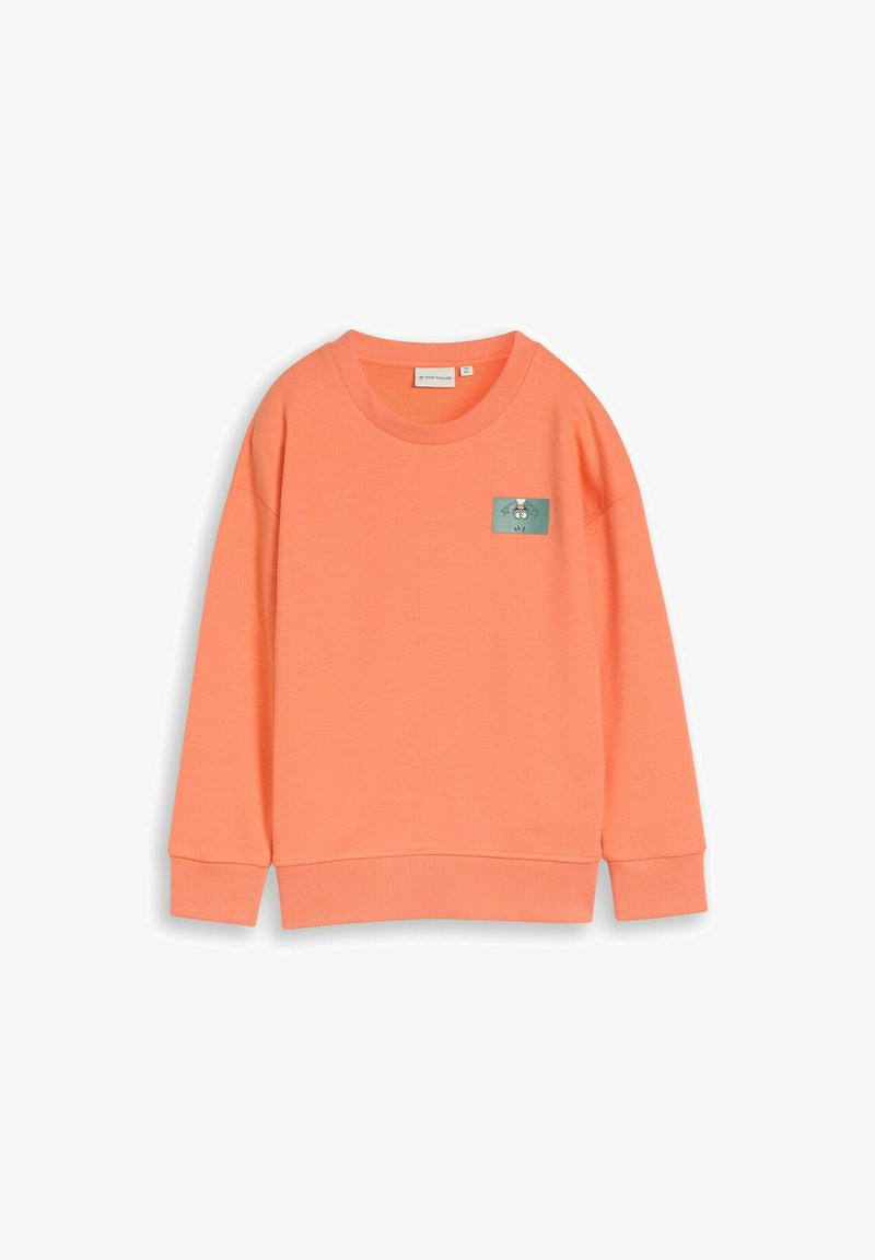 Sweat-shirt corail orange à col rond, manches longues, avec un petit patch rectangulaire représentant un chien dessin animé sur la poitrine gauche.