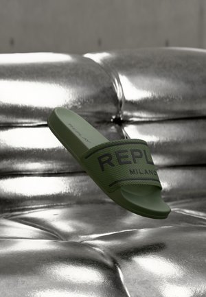 Roheline kummist libisev sandaal, millel on tekstuuriga rihm ja musta värvi "REPLAY MILANO" logo. Metallikpinnaga sile ja poolläikiv viimistlus.