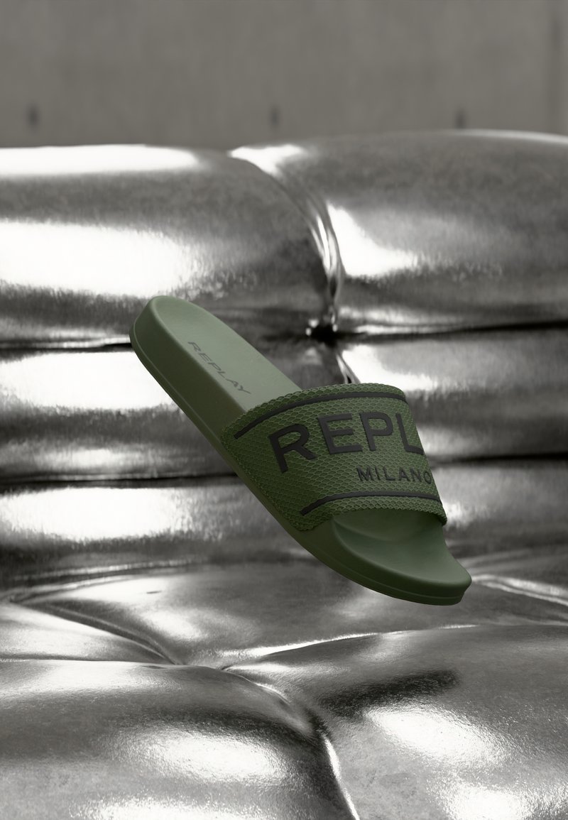 Πράσινο λαστιχένιο σανδάλι με υφασμένο λουρί που φέρει το μαύρο λογότυπο "REPLAY MILANO". Λείο, ημίγυαλιστερό φινίρισμα σε μεταλλική επιφάνεια.