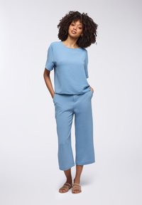 Completo due pezzi di un blu chiaro composto da una maglietta ampia e testurizzata con maniche corte e pantaloni cropped a gamba larga. Design semplice e vestibilità casual.