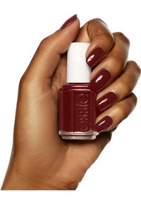 Bottiglia di smalto Essie con un tappo bianco tenuta in mano. Il colore è un borgogna profondo con una finitura lucida; le unghie sono dello stesso tono.