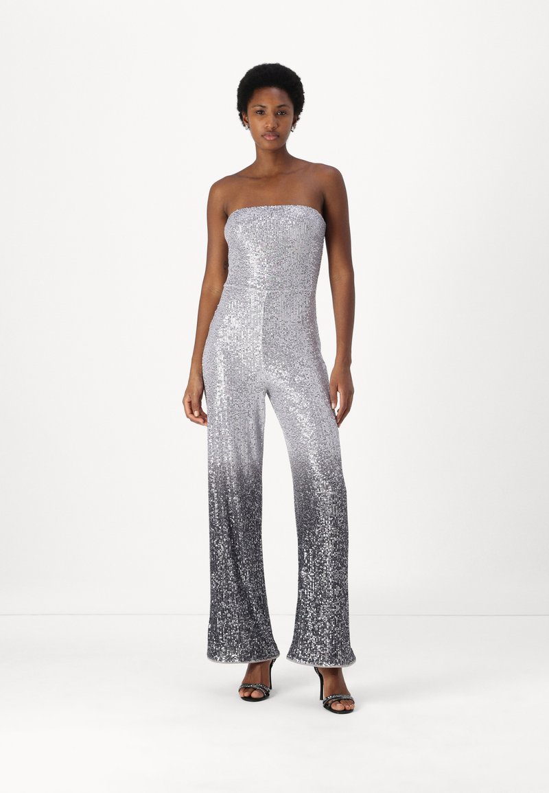 Sølvfarget sequins jumpsuit med stroppeløs design, vide ben og en gradient fra lys til mørk nederst. Jevn, reflekterende tekstur.