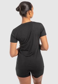 Sort kortærmet t-shirt lavet af blødt stof, med en rund halsudskæring og en afslappet pasform, parret med sorte shorts.