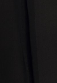 Sort stof med en glat tekstur, der har subtile folder og draperinger, hvilket skaber et enkelt, elegant udseende. Ingen synlige mønstre eller hardware.