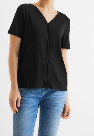 Top negro de manga corta con diseño de escote en V, que presenta un pliegue central y una textura suave. Combinado con jeans azules, ofrece un look casual.