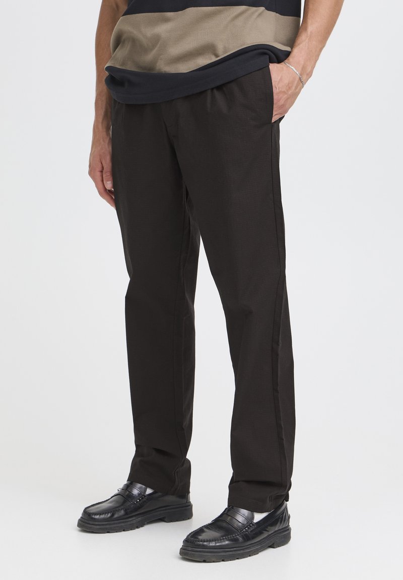 Pantalones negros de pierna recta hechos de tela texturizada, con bolsillos laterales y un diseño limpio y entallado, combinados con mocasines negros.