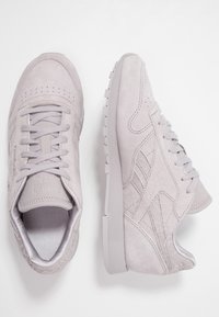 Grå mockaskor för sport med lågt skaft, texturerade sidopaneler, matchande snören och en gummisula, som har perforerade detaljer.