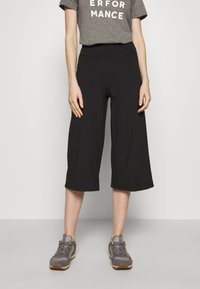 Black culottes made of soft fabric, mid-calf length, featuring a smooth waistband. Paired with a gray graphic T-shirt and gray sneakers.