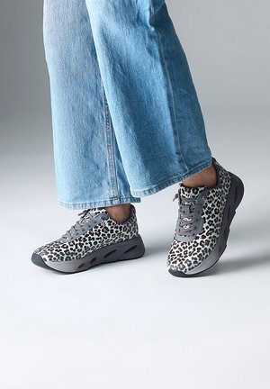 Baskets à imprimé léopard gris et blanc avec un design à lacets, semelle rembourrée et bout rond, associées à un jean large bleu clair.