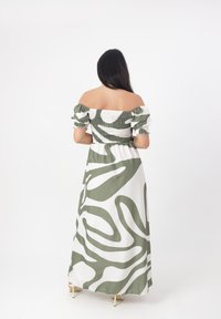 Vestito lungo verde e bianco con design off-the-shoulder, dotato di corpetto arricciato e motivi astratti ondulati. Tessuto con texture liscia.
