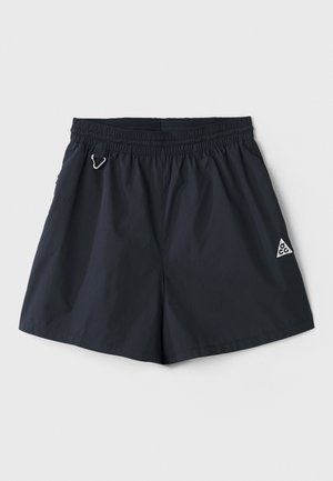 Kerged navy sinised lühikesed püksid elastse vöökoha, küljetaskute ja väikese kolmnurkse logoga; sile tekstuur, minimalistlik disain.