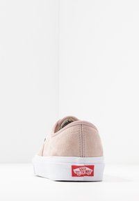 Sneaker Vans in suede rosa chiaro vista dal retro, che mostra la suola bianca e il logo rosso "Vans Off The Wall" sul tallone.