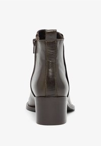 Bruine leren enkellaars met een gladde textuur, ronde neus en een blokhak van 7,5 cm. Voorzien van een zijrits en contrasterende stiksels.