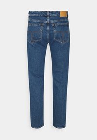Blue denim jeans with straight legs, two back pockets with stitching detail, and a brown leather patch on the waistband.