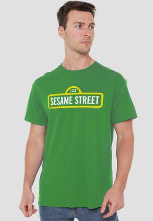 Grünes Baumwoll-T-Shirt mit einem gelb-weißen "123 SESAME STREET" Grafikdesign auf der Vorderseite, kurzen Ärmeln und einem Rundhalsausschnitt.