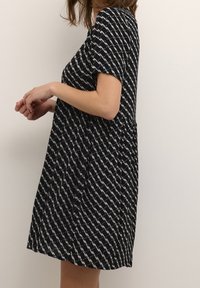 Schwarz-weiß gemustertes kurzes Kleid mit kurzen Ärmeln, A-Linien-Silhouette, leichtem Stoff und dezentem Strukturdetail.