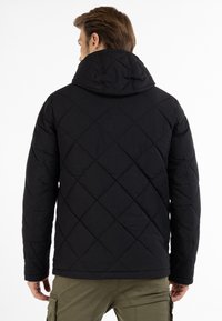 Sort quilted jakke med hætte, der har et geometrisk diamantmønster og en glat, strømlinet tekstur. Sorte metaldetaljer.