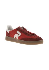 Baskets en suede rouge avec des accents blancs, lacets plats et semelle en caoutchouc translucide. Présente un logo sur le côté et un design bas.