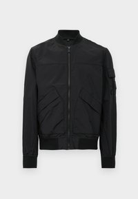 Black bomber jacket with a zip front, ribbed cuffs and hem, two angled front pockets, and a utility-style pocket on the left sleeve.
