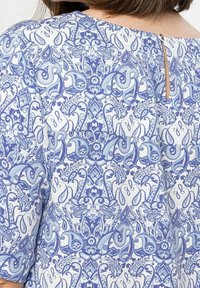 Blaue blumengemusterte Bluse mit aufwendigen Paisley- und Blumenmotiven, Rundhalsausschnitt und einem kleinen Schlüsselloch hinten.