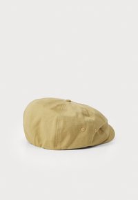 Lichtbeige pet met een ronde vorm, gemaakt van gestructureerde stof, met een vlakke rand en twee ventilatiegaten aan de zijkant.