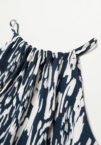 Navy and white patterned fabric top with gathered elastic neckline and thin straps, featuring a textured and flowing design.