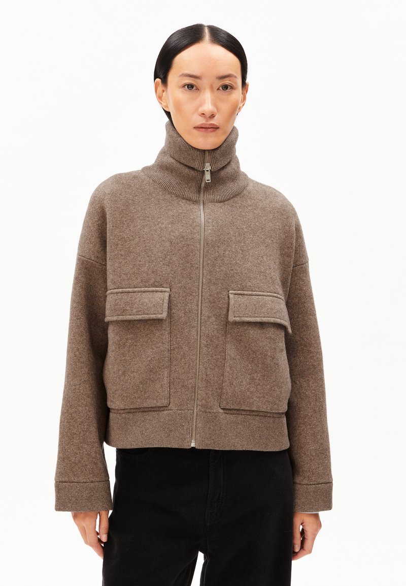 Brun, zip-up jacka med hög krage, med två framfickor och ribbad mudd. Mjuk, texturerad denim med avslappnad passform.