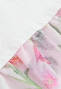 Der weiße Stoff an der Oberseite ist glatt, während der untere Teil eine durchsichtige rosa Netzschicht mit floralen Mustern in Rosa- und Grüntönen aufweist.