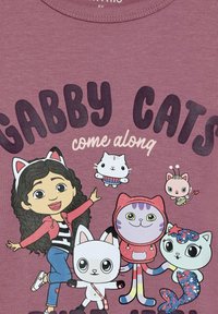 Grafisches T-Shirt in Mauve mit Cartoon-Charakteren: ein Mädchen mit lockigem Haar, eine weiße Katze, eine lila Katze und zwei weitere bunte Katzen.