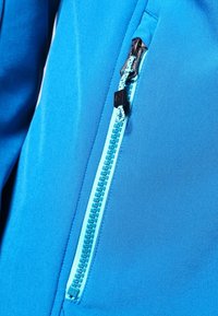 Blauwe softshelljas met een contrasterende aqua rits, een gladde textuur en een slank ontwerp. De rits heeft een kleine zwarte accent.