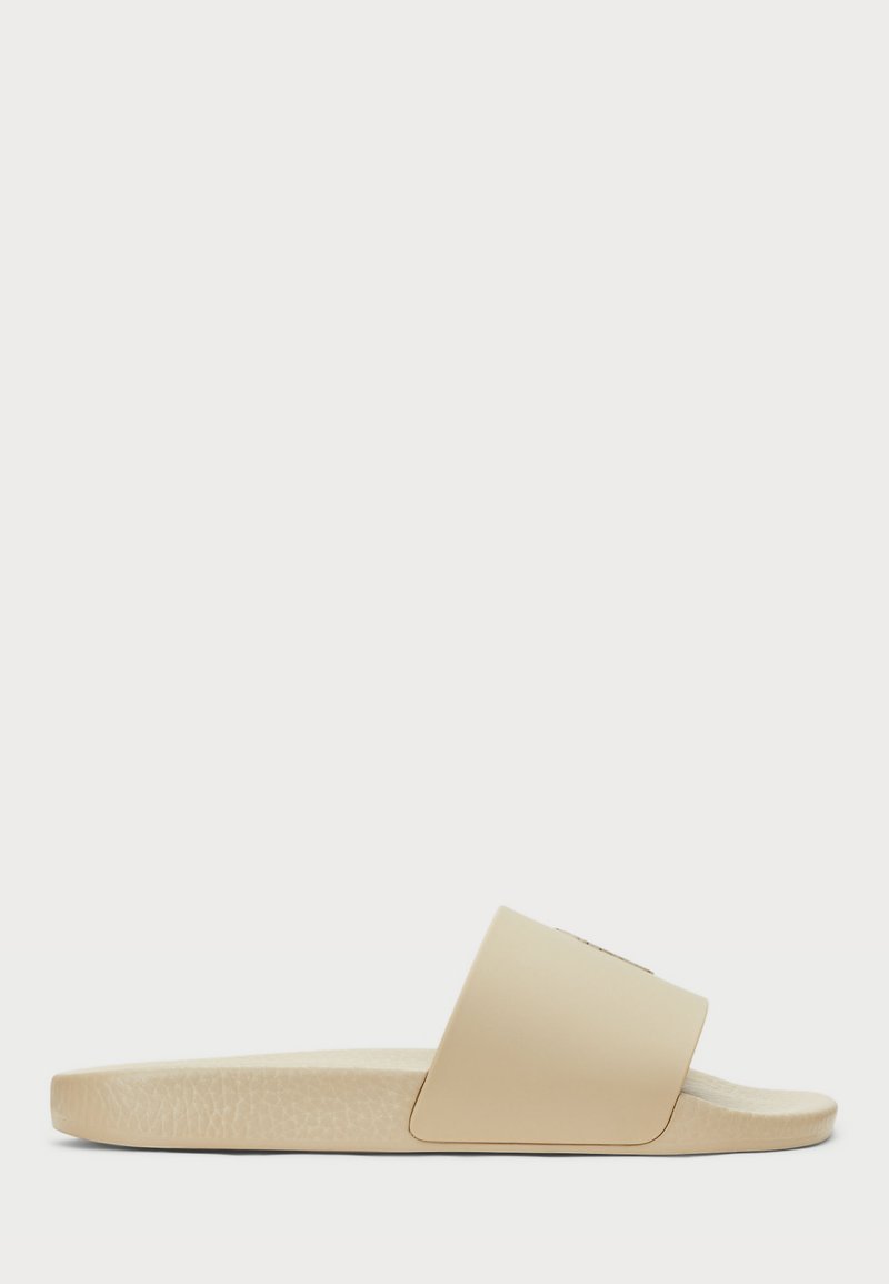 Beige csúszós szandál széles, sima pánttal és texturált talppal. Könnyű kialakítás, minimalista esztétikával.