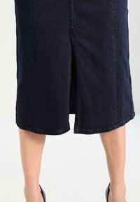 Tmavě modrá midi sukně z denimu s předním rozparkem, která má hladký lem a jemnou texturu. Nosit s černými lodičkami na vysokém podpatku.