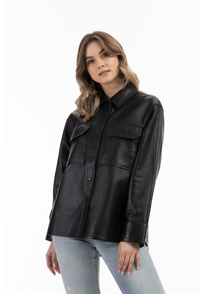 Giacca camicia in pelle nera con chiusura a bottoni, due tasche sul petto, maniche lunghe e una vestibilità rilassata. Texture liscia e finitura lucida.