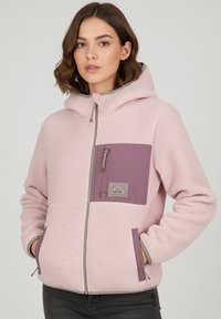 Fleece jacket in light pink with a hood. Features a purple chest pocket and gray accents. Zipper closure and side pockets. Soft texture.