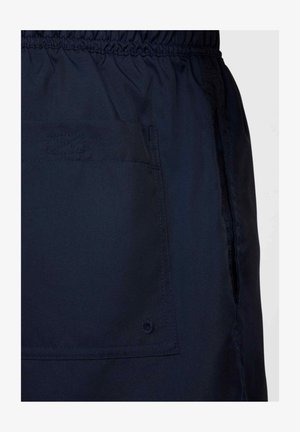 Tummansiniset shortit, jotka on valmistettu kevyestä kankaasta ja joissa on joustava vyötärö, sivutaskut sekä koristeellinen ommeltu kuvio taskussa.