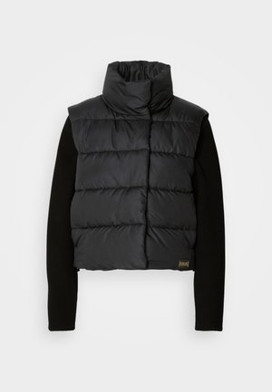 Mustamugune lühike puffjakker kõrge kaelusega ja ristkülikukujulise õmbluse mustriga. Omab mustade soonikulevatega pikki varrukaid ja logodetaili allservas.