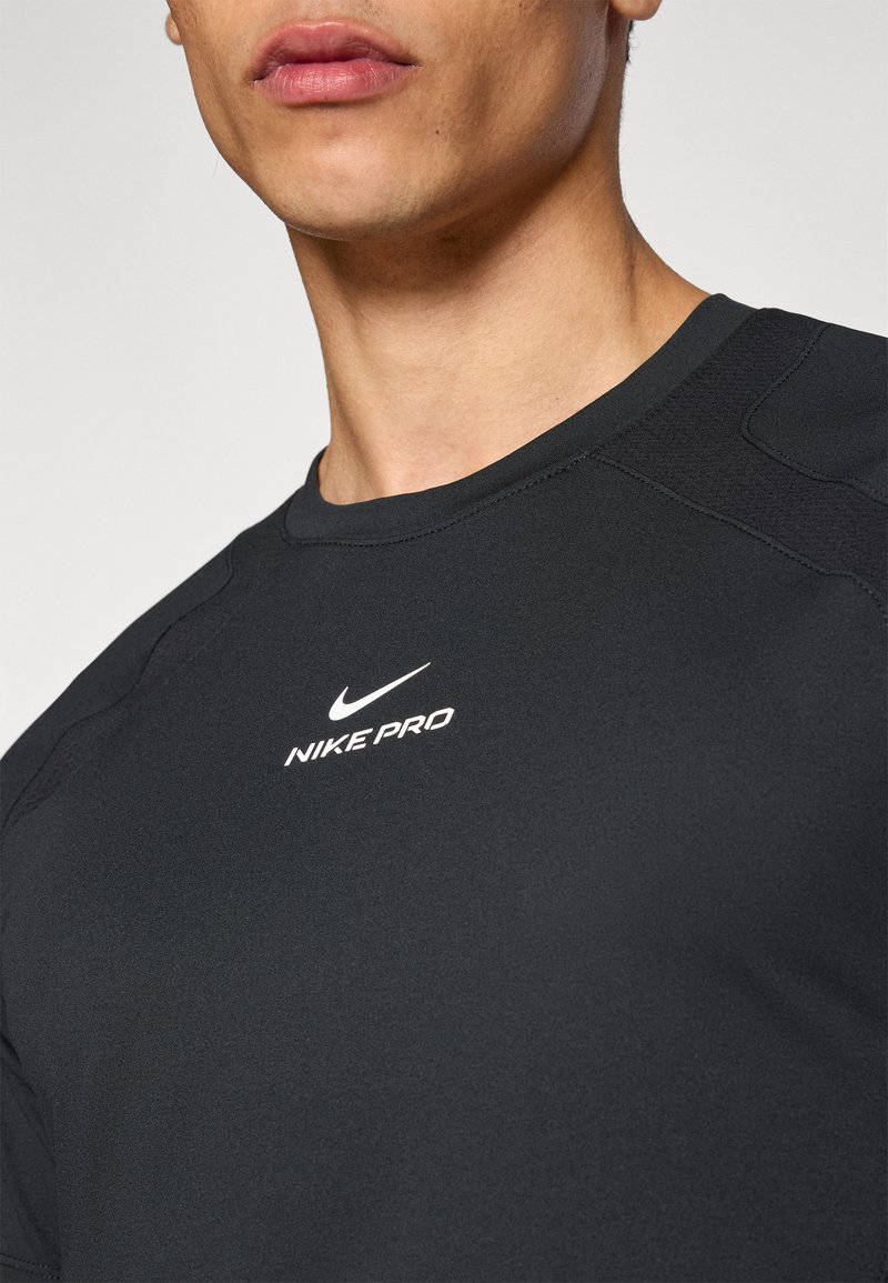 Black athletic shirt made of smooth, stretchy material with short sleeves. Features a round neckline and a white Nike Pro logo on the chest.