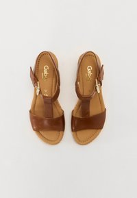 Brown leather sandals with a T-strap design, featuring a buckle closure and stitched edges on a beige sole. Gabor logo on insole.