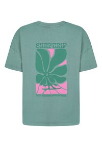 Groene katoenen t-shirt met een groot grafisch ontwerp van overlappende vormen in groen en roze, met de tekst "SURFTRIP" in het midden. Korte mouwen en een ronde hals.