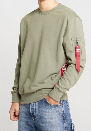 Sweatshirt vert olive en mélange de coton, avec une poche à manches zippée et un accent latéral rouge avec du texte. Poignets et ourlet côtelés.