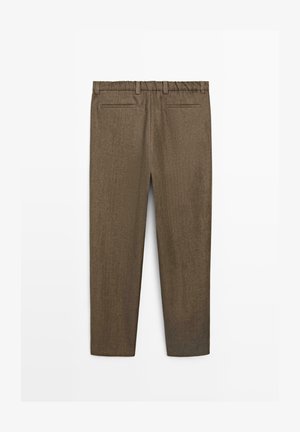 Braune maßgeschneiderte Hose mit elastischem Bund, Gürtelschlaufen und zwei Leistentaschen auf der Rückseite, von hinten vor weißem Hintergrund gezeigt.