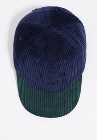 Cappello in corduroy con parte superiore blu navy e visiera verde, caratterizzato da righe verticali e branding ricamato sul davanti.
