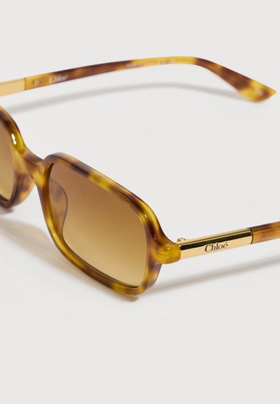 Lunettes de soleil rectangulaires en écaille de tortue avec verres dégradés marron et branches en métal doré gravées du logo "Chloé".