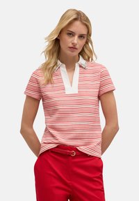 Polo a rayas rojas y blancas con un cuello blanco, que presenta detalles decorativos en el cuello, combinado con pantalones rojos.