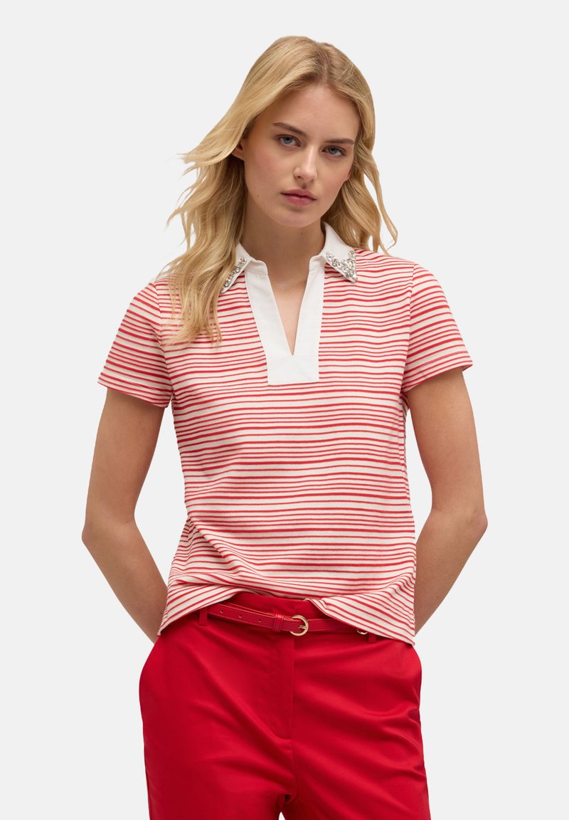 Polo a rayas rojas y blancas con un cuello blanco, que presenta detalles decorativos en el cuello, combinado con pantalones rojos.
