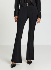 Schwarze, ausgestellte Hosen aus dehnbarem Stoff mit hoher Taille, dekorativer Gürtelschnalle und Nahtverzierungen entlang der Beine.